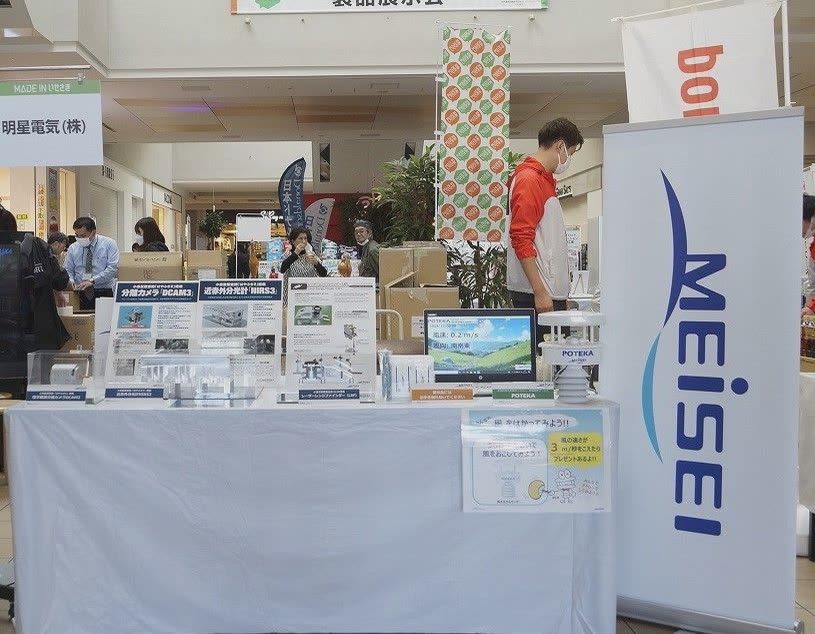 明星電気の展示台に気象観測機器「POTEKA」やカメラの説明パネルが並び、横に MEISEI のバナーが立っている様子